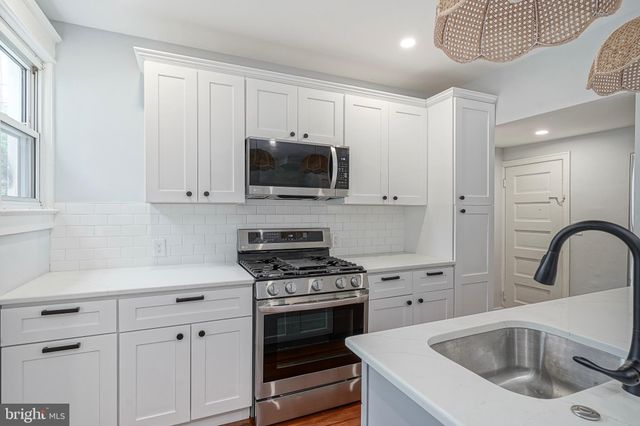 a kitchen with white cabinets a sink dishwasher and a stove with wooden floor