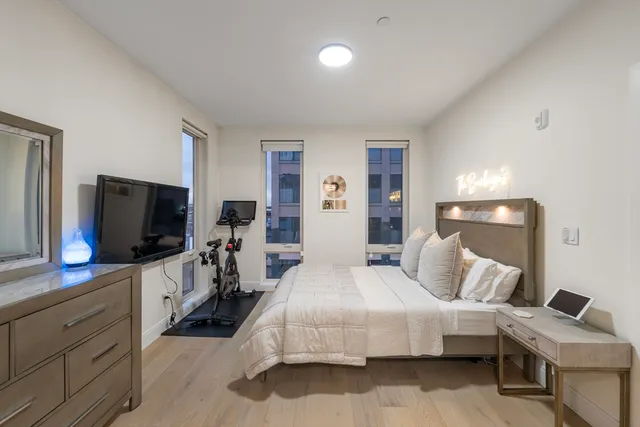 a bedroom with bed and a flat tv screen on dresser