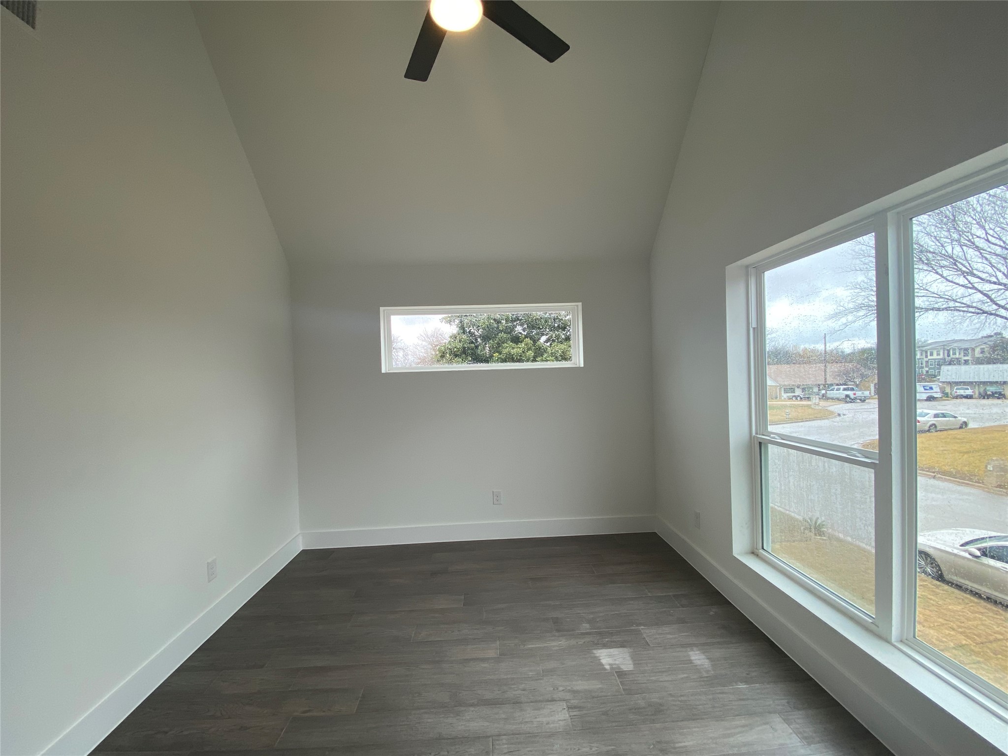 1916 Webberville Road, Unit B Austin, TX 78721 - Photo 19 of 25 Vaulted ceiling room featuring wood-finish flooring, a contemporary ceiling fan, and multiple windows