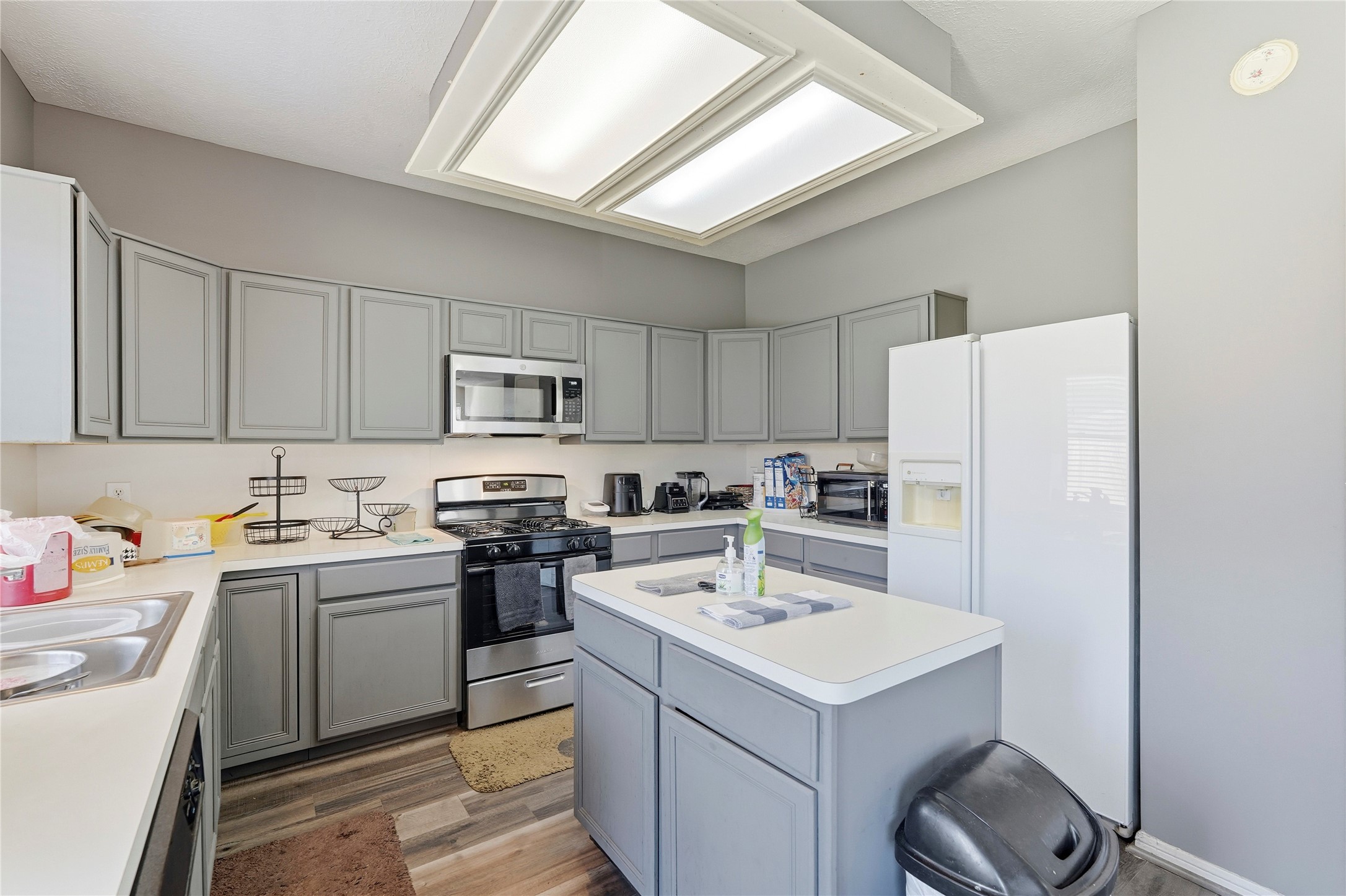 8706 Lone Maple Drive Houston, TX 77083 - Photo 16 of 27 a kitchen with a sink a stove a refrigerator and white cabinets