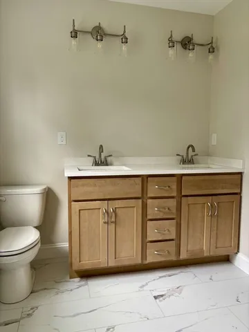 a bathroom with a granite countertop sink and a toilet
