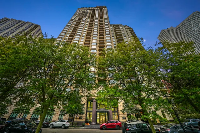 aerial view of a residential apartment building with a yard and parking spaces