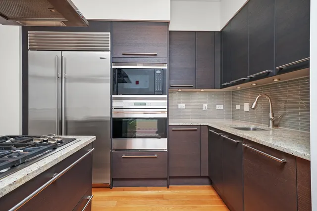 a kitchen with kitchen island granite countertop a sink stainless steel appliances and cabinets