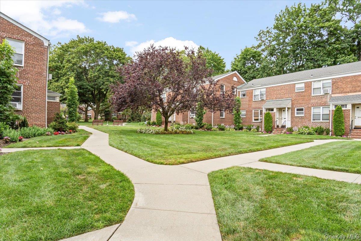 77 Edwards Street, Unit 2A Roslyn Heights, NY 11577 - Photo 18 of 29 a view of a white house with a big yard and potted plants