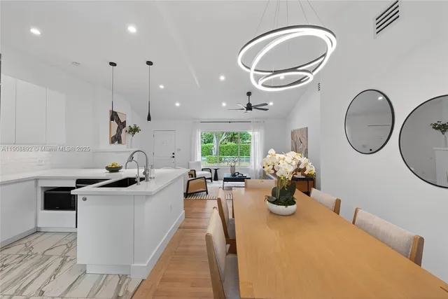 a dining room with stainless steel appliances kitchen island granite countertop a table chairs and a refrigerator