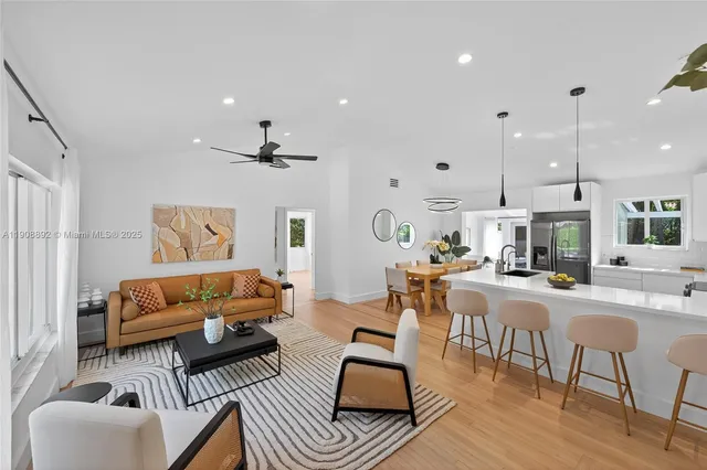 a living room with furniture kitchen view and a chandelier