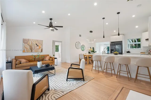 a living room with furniture kitchen view and a chandelier