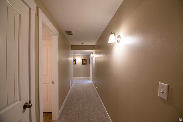 646 East 1400th Street North Mapleton, UT 84664 - Photo 34 of 78 Corridor featuring light beige wall paint, white trim, and wall-mounted sconces providing illumination