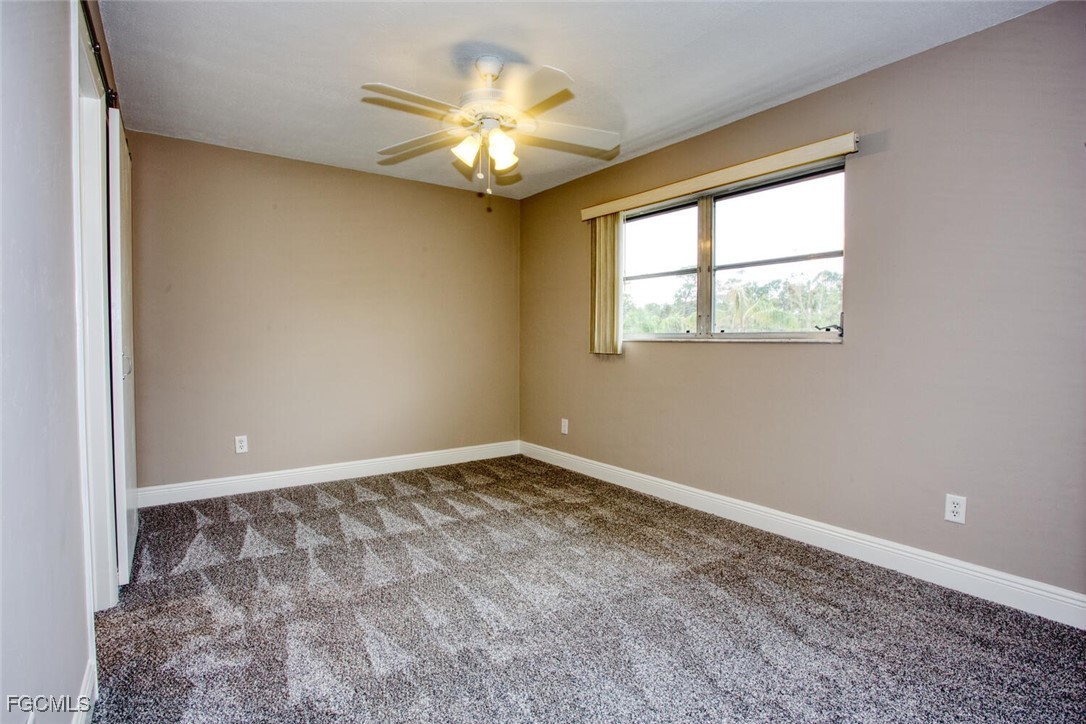 5917 Littlestone Court, Unit 118 North Fort Myers, FL 33903 - Photo 10 of 20 an empty room with a chandelier fan and windows