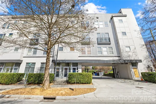 a front view of a building with garden and parking