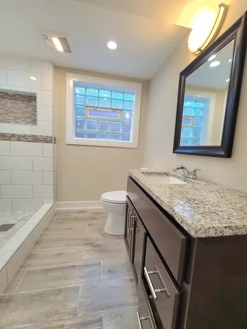 a bathroom with a granite countertop sink a toilet and with shower
