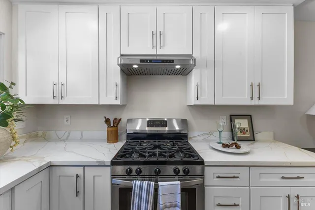 a kitchen with granite countertop white cabinets and stainless steel appliances