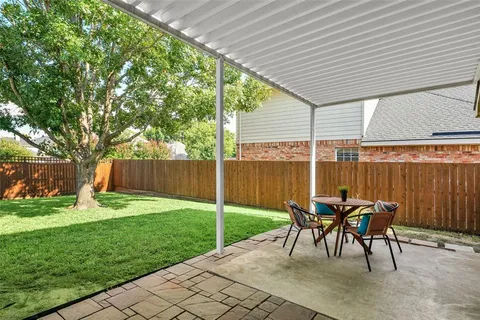 a view of a patio with table and chairs under an umbrella with a small yard