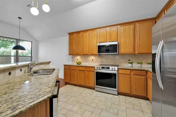 a kitchen with stainless steel appliances granite countertop a sink stove and refrigerator