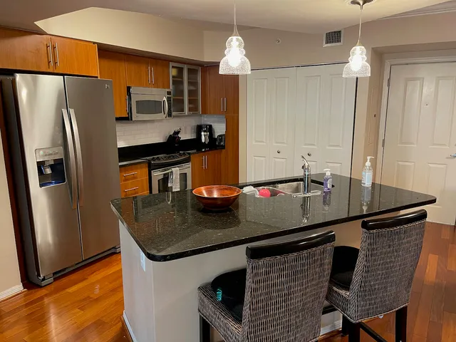 a kitchen with granite countertop a sink cabinets and stainless steel appliances