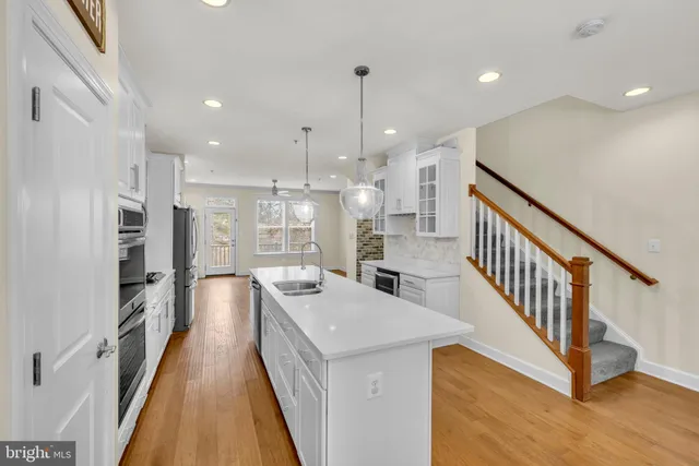 a large white kitchen with wooden floor and a window
