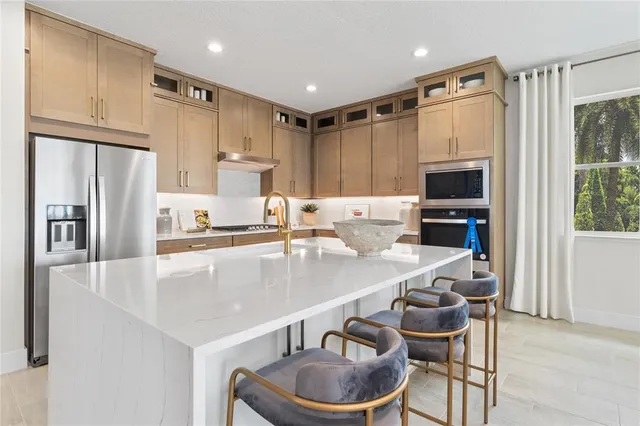 a kitchen with kitchen island granite countertop stainless steel appliances a sink a stove a refrigerator cabinets and a dining table