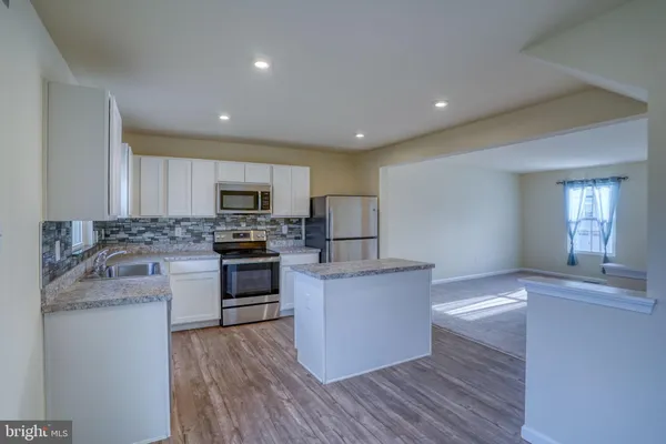 a kitchen with granite countertop a stove top oven and cabinets