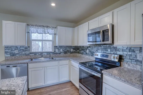 a kitchen with stainless steel appliances granite countertop a sink stove and microwave