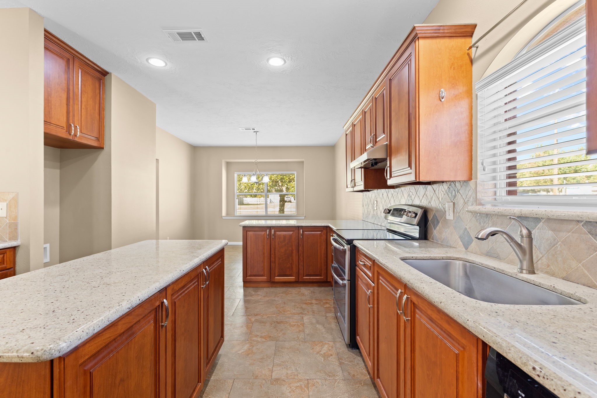 24236 Stuebner Airline Road Tomball, TX 77375 - Photo 9 of 39 a kitchen with granite countertop a sink a counter space appliances and cabinets