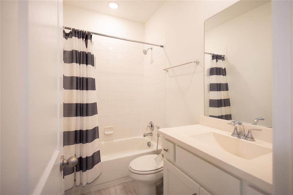 3017 Andorra Road McKinney, TX 75071 - Photo 26 of 40 Bathroom featuring a built-in tub with shower, white subway tile surround, single vanity with integrated sink, chrome fixtures, and wood-finish flooring
