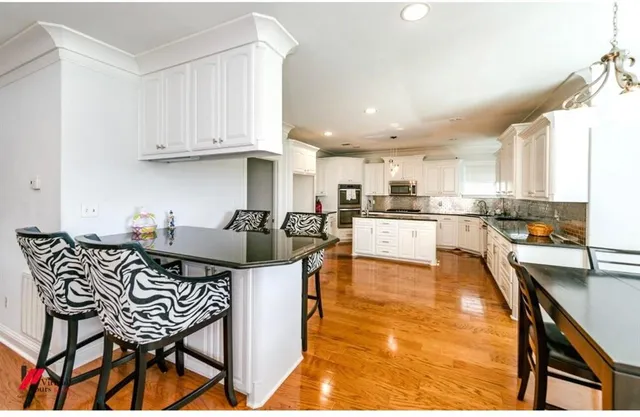 a kitchen with stainless steel appliances kitchen island granite countertop a table chairs sink and cabinets
