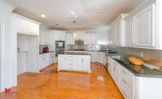 a large kitchen with stainless steel appliances granite countertop a sink and cabinets