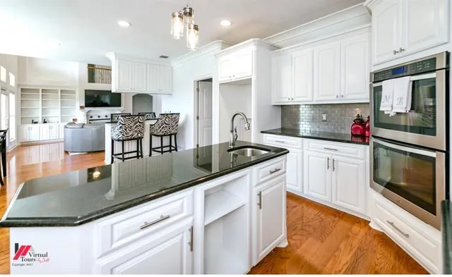a kitchen with stainless steel appliances granite countertop a sink dishwasher stove top oven and cabinets with wooden floor