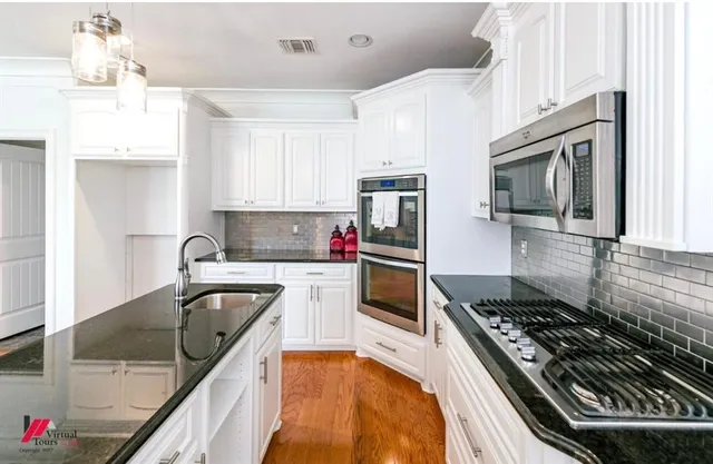 a kitchen with kitchen island granite countertop a sink stainless steel appliances and cabinets