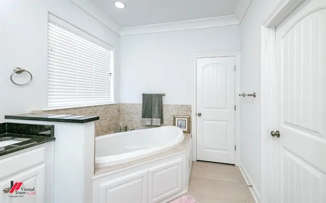 a bathroom with a granite countertop sink and a bathtub