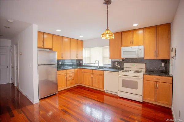 a kitchen with stainless steel appliances granite countertop a refrigerator a sink dishwasher a stove and white cabinets with wooden floor