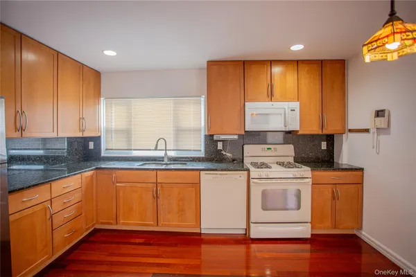 a kitchen with stainless steel appliances granite countertop a stove a sink and white cabinets with wooden floor