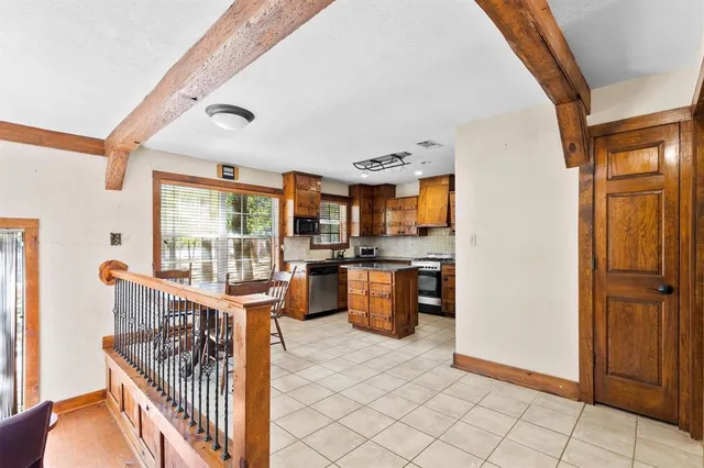 a room with granite countertop lots of wooden cabinets a stove and a refrigerator