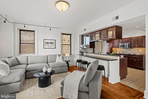 a living room with stainless steel appliances furniture a rug and a window