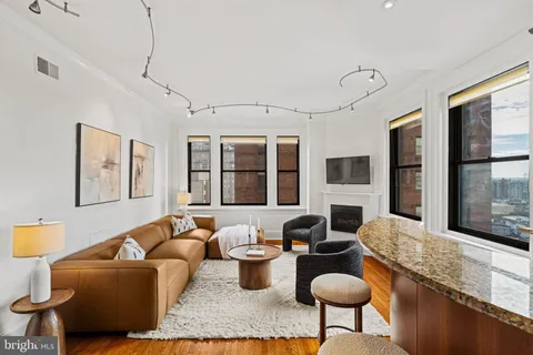a living room with furniture a flat screen tv and large windows