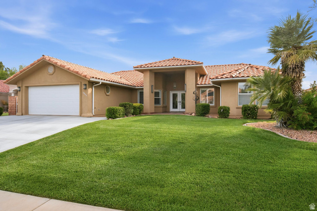 1985 West Rivers Edge Lane St. George, UT 84770 - Photo 9 of 42 Mediterranean / spanish house with french doors, an attached garage, stucco siding, concrete driveway, and a front lawn