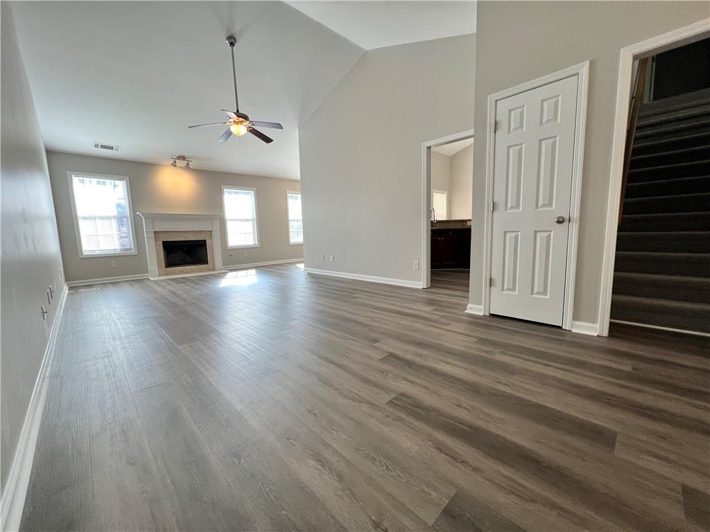 an empty room with wooden floor fireplace and windows