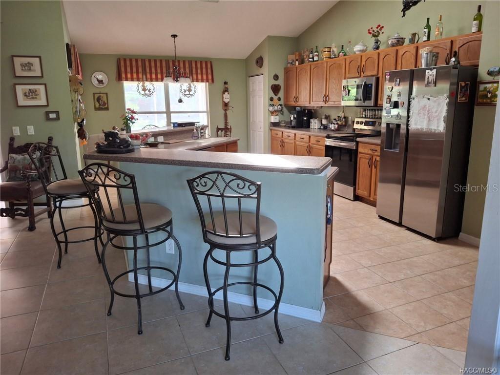 4295 North Bridge Road Beverly Hills, FL 34465 - Photo 10 of 79 a kitchen with stainless steel appliances a table chairs and a refrigerator