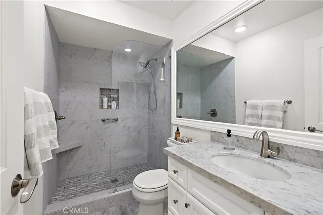 a bathroom with a granite countertop sink mirror toilet and shower