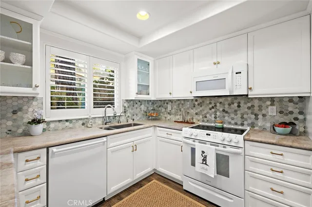 a kitchen with white cabinets appliances a sink and a window