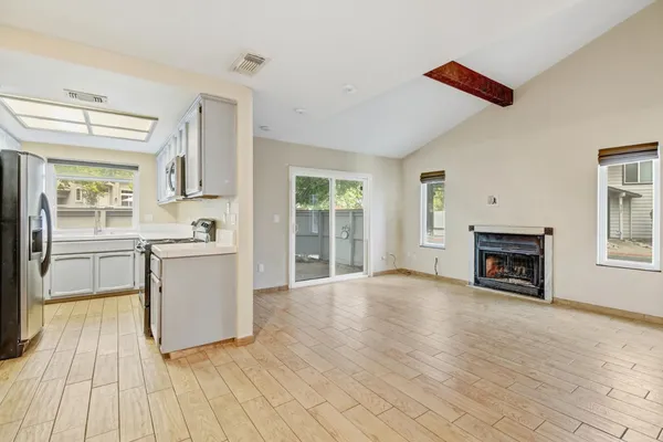 a view of kitchen with granite countertop a stove top oven a sink dishwasher and a fireplace with wooden floor