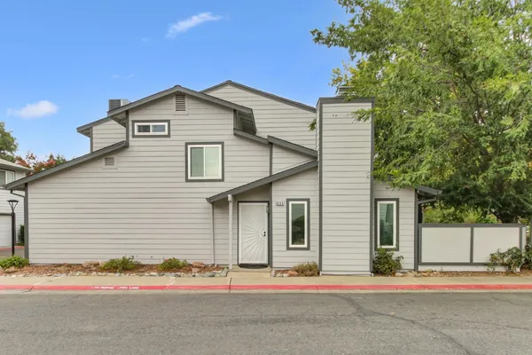 a white house that has a tree on the side of it
