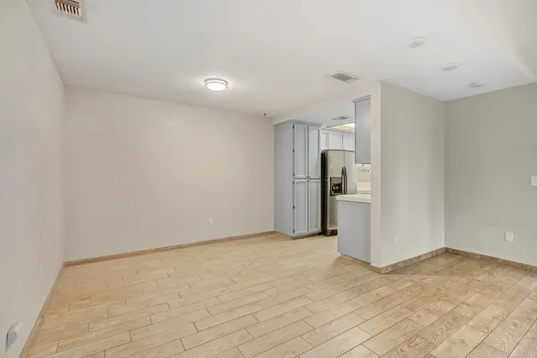 a view of an empty room with kitchen and a window