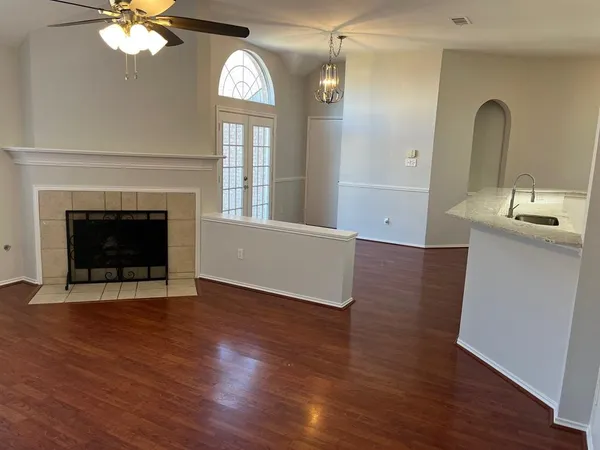 an empty room with wooden floor fireplace and windows