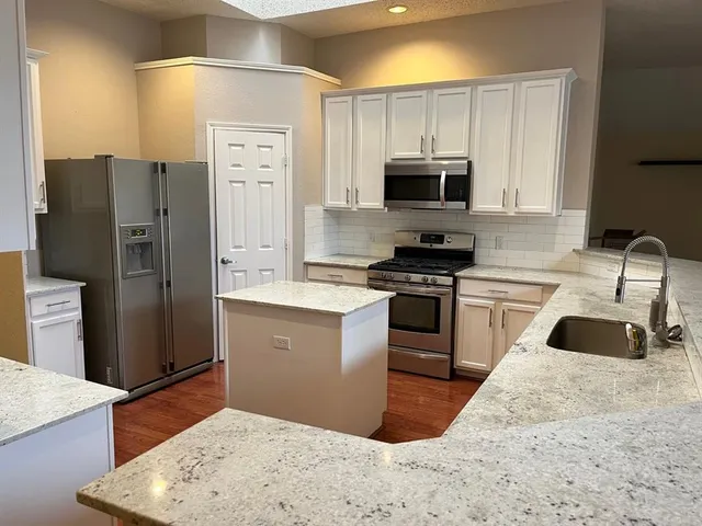 a kitchen with granite countertop a refrigerator sink and stove
