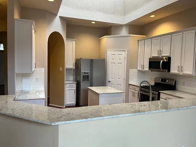 a kitchen with stainless steel appliances granite countertop a sink a stove and a refrigerator