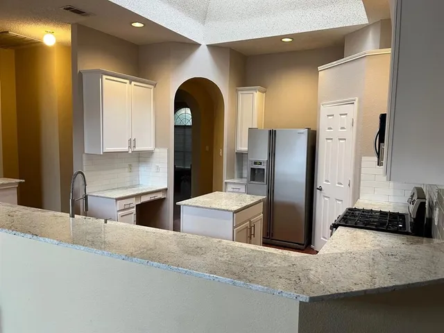 a kitchen with stainless steel appliances kitchen island granite countertop a refrigerator and a sink