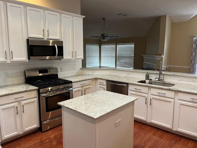 a kitchen with stainless steel appliances granite countertop a sink stove and microwave
