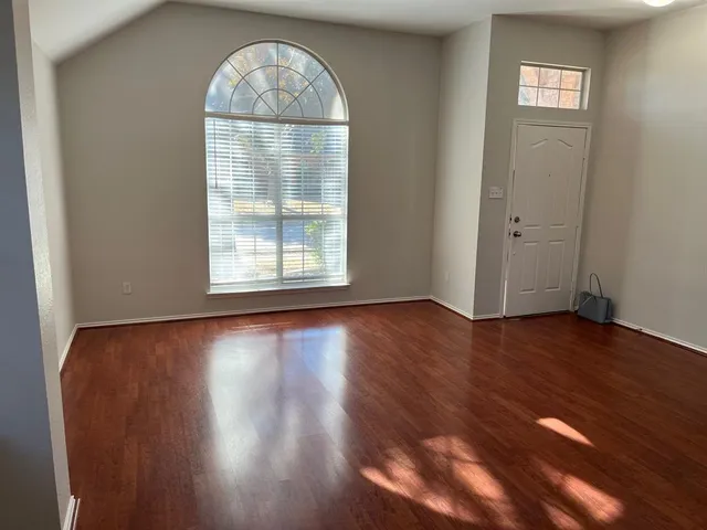 an empty room with wooden floor cabinet and windows