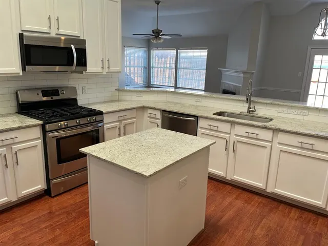 a kitchen with stainless steel appliances granite countertop a sink stove and microwave